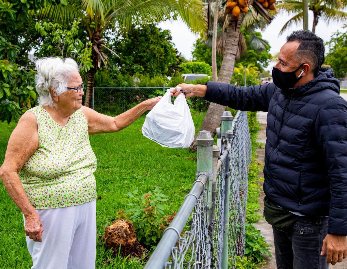 Colombian comedian Julio Rodríguez gives a meal to a senior lady while out on delivery for Lean Culinary Services LLC, a subcontractor that delivers meals, to the needy all over Miami-Dade, in Homestead, Florida on Tuesday, May 26, 2020. Later in the evenings Rodriguez performs in his YouTube show called Politicamente en su recto with other renown Latin American comedians.
