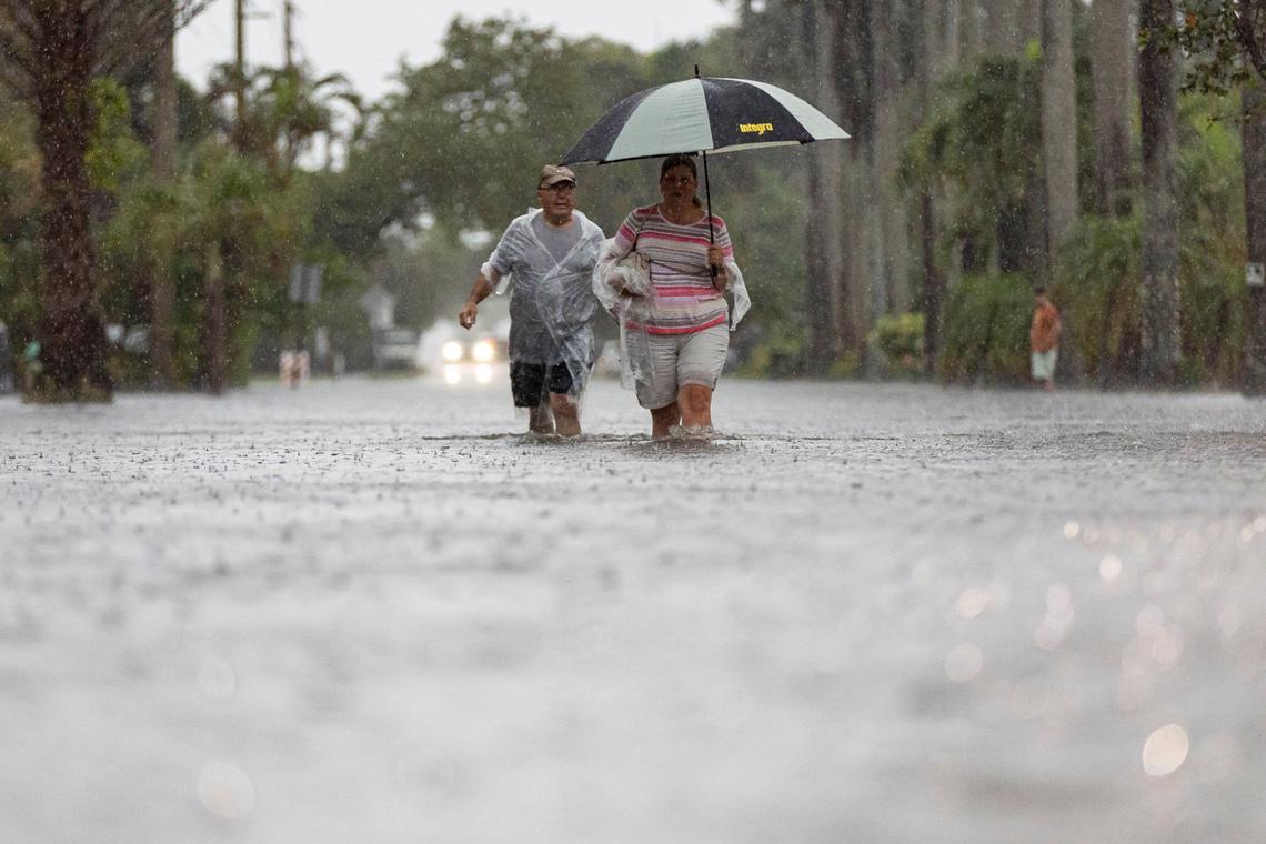 Jim Comunale and Pam Mervos walk down Arthur Street as heavy rain floods the surrounding neighborhood on Wednesday, June 12, 2024, in Hollywood, Fla.