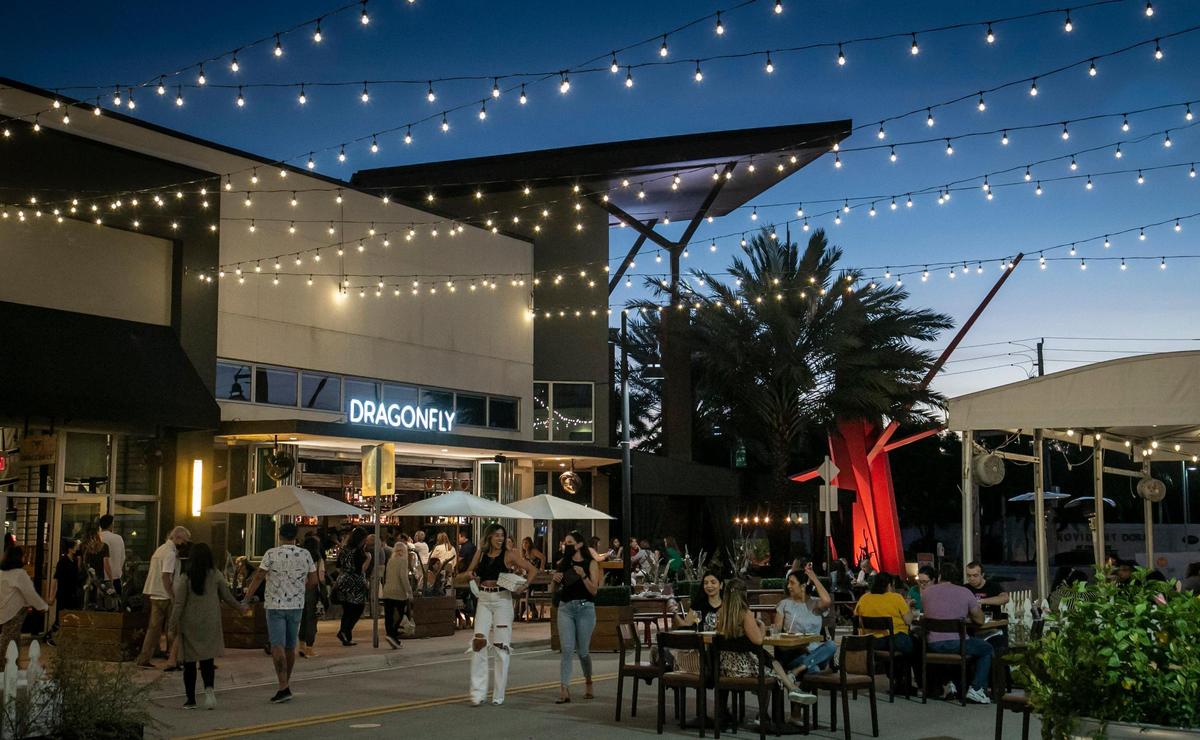Doral, Florida, March 23, 2021 -People enjoy outdoor dining in bustling Main Street in Doral. Popular restaurants with locations elsewhere are eyeing Doral for their second locations. Doral has evolved in the last few years from a “logistics/warehouse” district to a place where residents can live, work and “play.” The city is trying to create a reputation as an art nexus; a central part of its downtown area has recently been rebranded as an arts district.