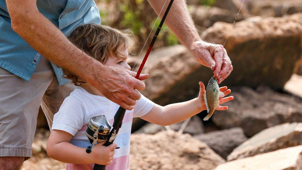 Wells Cannon catches a fish with his Grandpa Ray at Arcadia Lake in Edmond, Okla., on Friday, May 26, 2023.