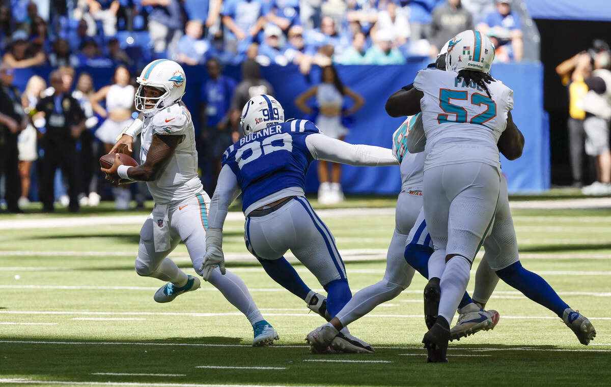 Miami Dolphins quarterback Tua Tagovailoa (1) is chased by Indianapolis Colts defensive tackle DeForest Buckner (99) during the first half of an NFL game at Lucas Oil Stadium on Sunday, Sept. 7, 2025, in Indianapolis, Indiana.