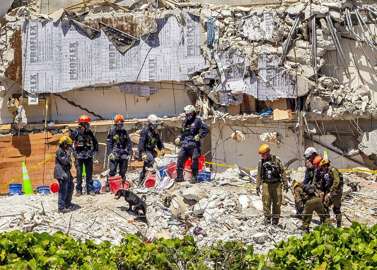 Rescuers and a rescue dog work on top of the rubble as the search and rescue mission continues at the Champlain Towers South site, nine days after the building collapsed, on Friday, July 2, 2021.