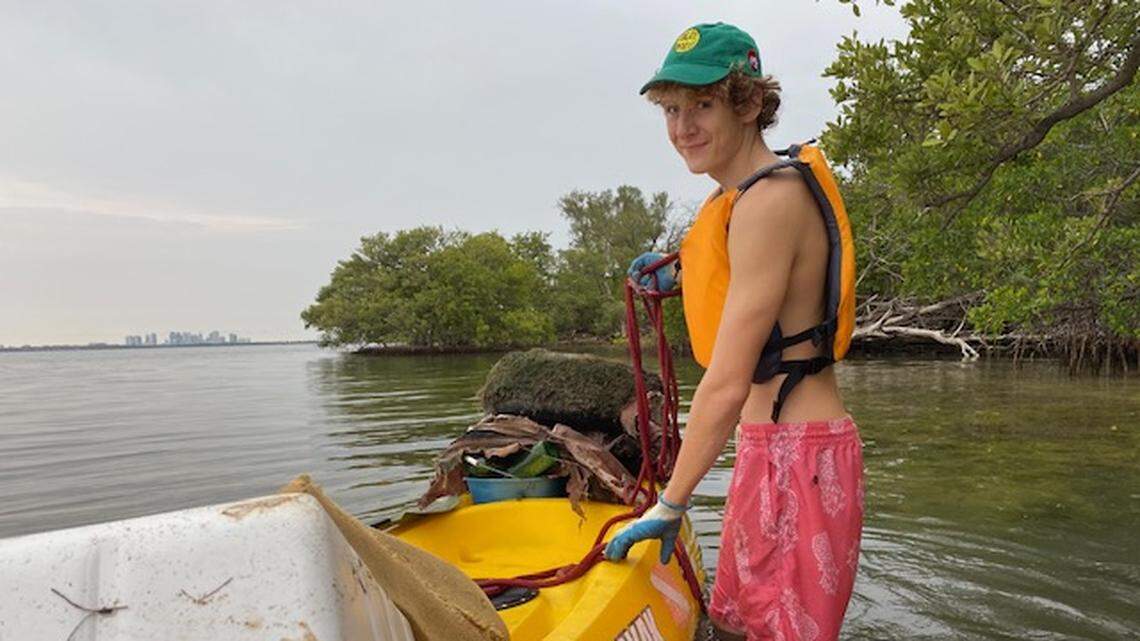 Carson Stanton-Sharpless stands by his trash-filled kayak after one of his cleanups at Bird Key in Biscayne Bay