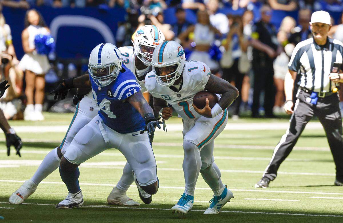 Miami Dolphins quarterback Tua Tagovailoa (1) is chased by Indianapolis Colts defensive end Tyquan Lewis (94) during the first half of an NFL game at Lucas Oil Stadium on Sunday, Sept. 7, 2025, in Indianapolis.