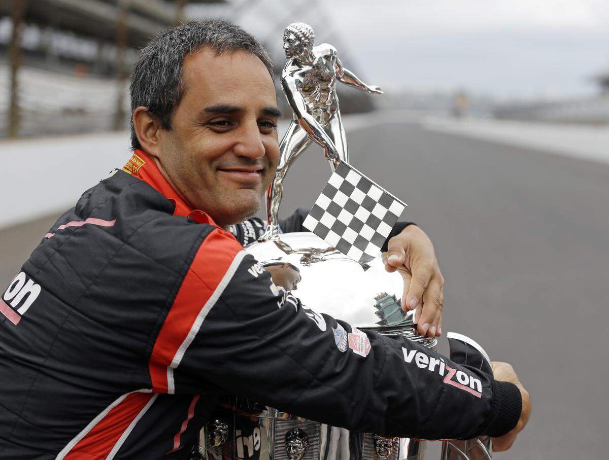 Miami resident Juan Pablo Montoya, of Colombia, hugs the Borg-Warner Trophy during the traditional winners photo session at Indianapolis Motor Speedway the day after winning the 2015 Indianapolis 500.