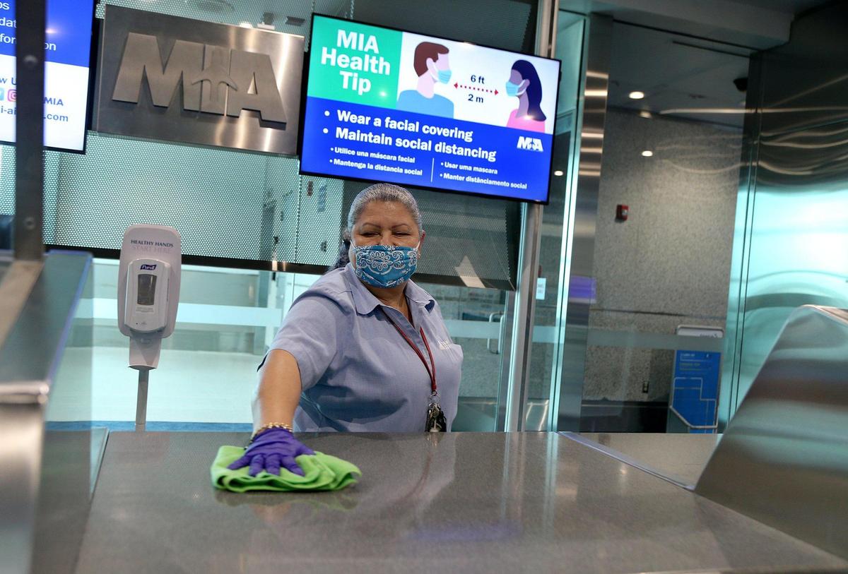 Alba Rios, an employee with CW Facility Services, sanitizes the counters at an American Airlines Concourse A gate at Miami International Airport, as American Airlines hosted the media to highlight the changes made to ensure the well-being of travelers as they return to the skies amid a surge of COVID cases in Florida, on Tuesday, June 30, 2020.