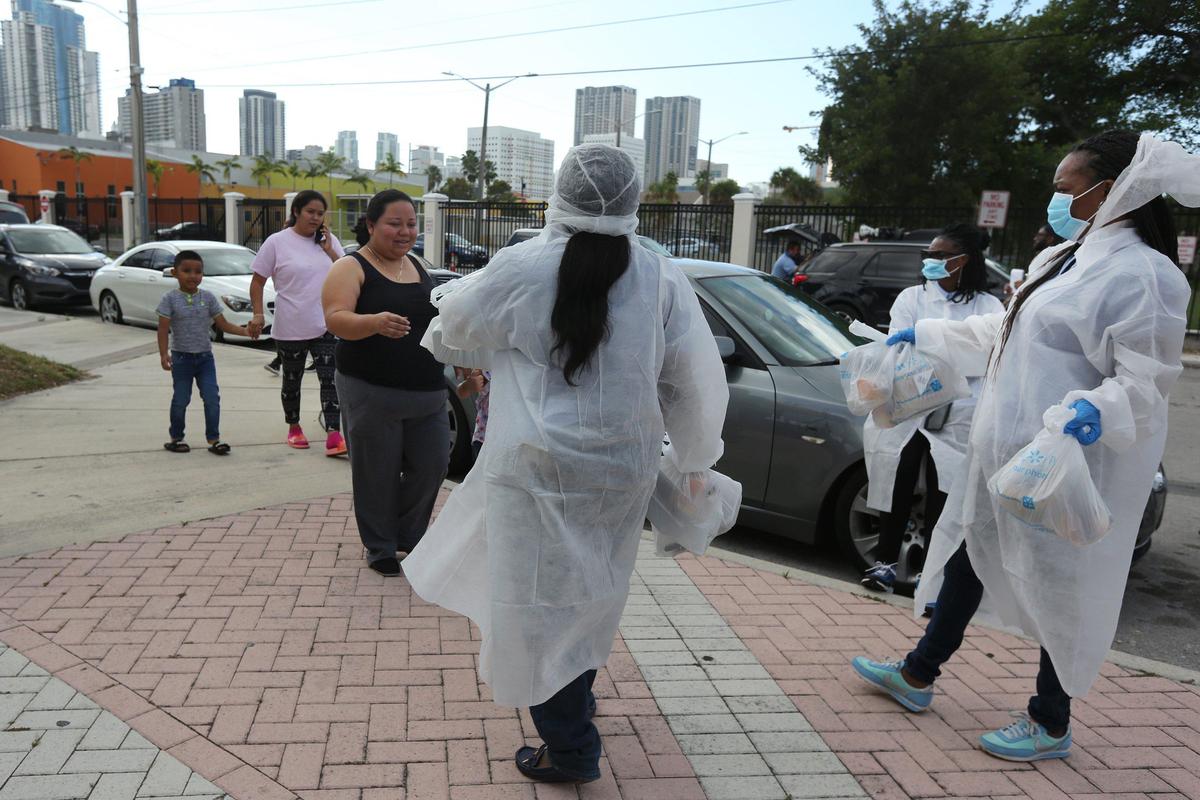 Overtown residents from L-R, Joandry Garcia,6, his mother, Cindy Franco, and their neighbor, Flor Vazquez, receive food from employees from Alonzo Mourning’s Overtown Youth Center on Wednesday, March 25, 2020. The center partnered with Deliver Lean to hand out breakfast and lunch meals to the residents of Overtown. The program distributes 100 packaged breakfasts and lunches, Monday, Wednesdays and Fridays from 9:30am until they run out of meals.