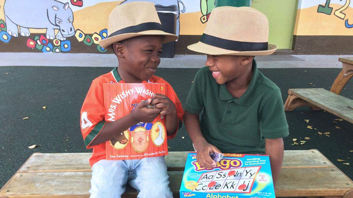 Little boys share a laugh as they hold on to books they are learning to read.