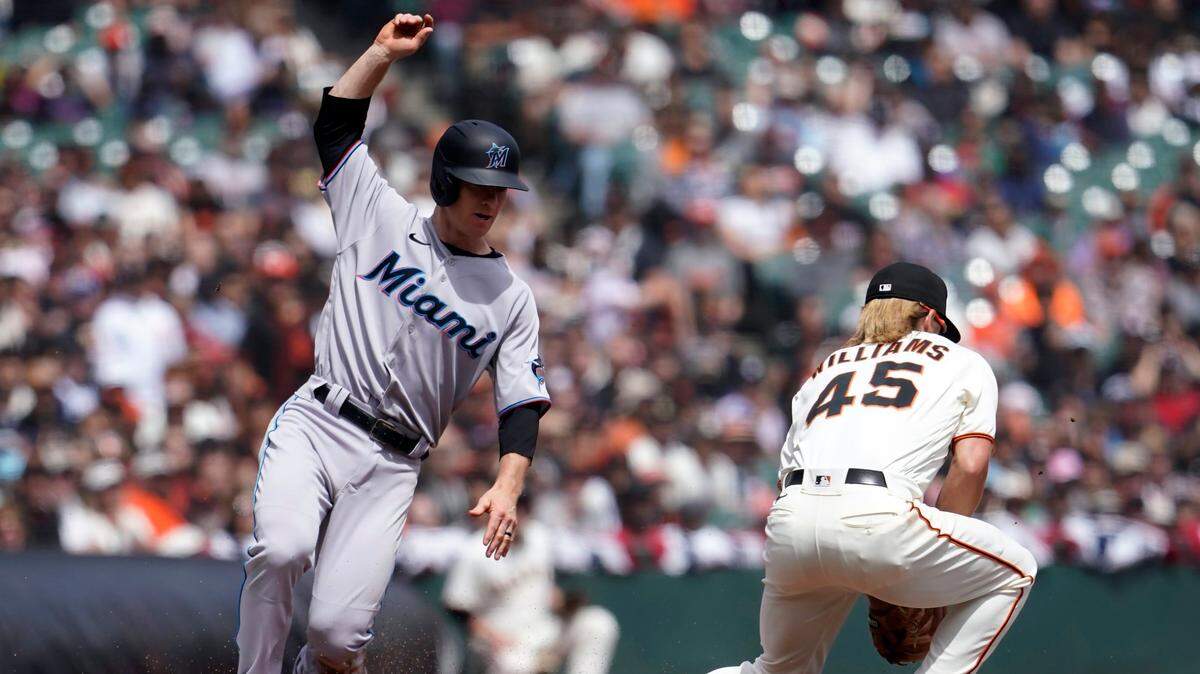 Miami Marlins’ Joey Wendle, left, slides safely into third base next to San Francisco Giants third baseman Luke Williams (45) during the second inning of a baseball game in San Francisco, Sunday, April 10, 2022. (AP Photo/Jeff Chiu)