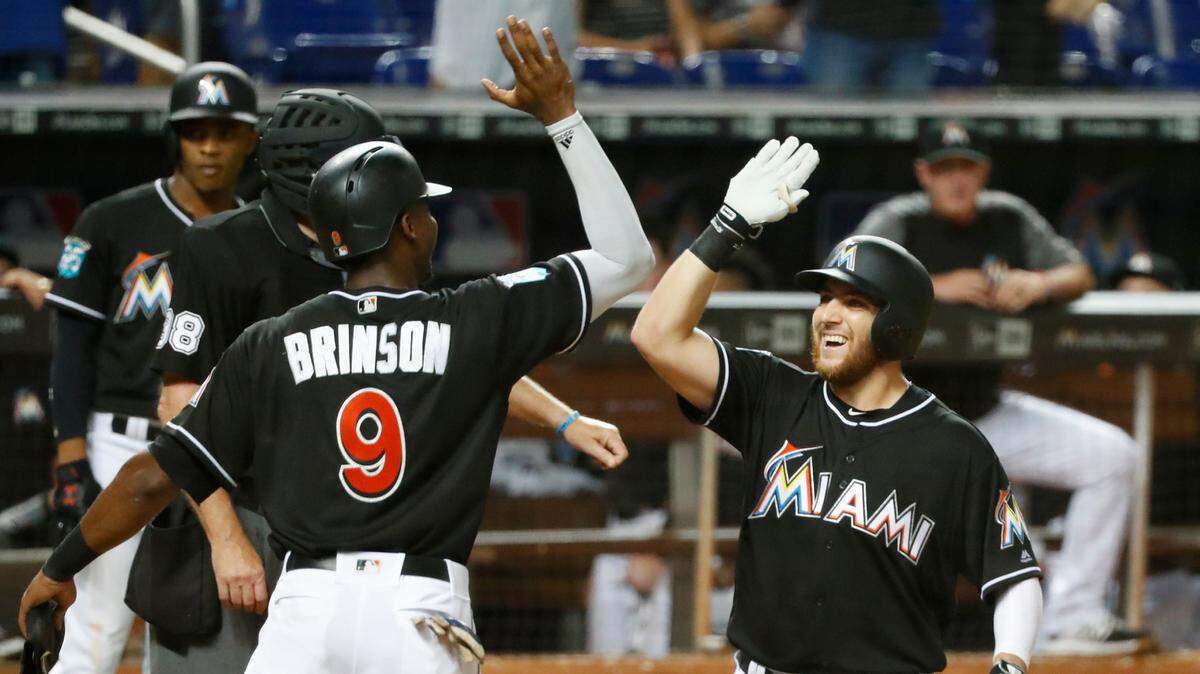 Miami Marlins’ Lewis Brinson (9) congratulates Austin Dean after Dean hit a home run also scoring Brinson during the sixth inning of a baseball game against the Cincinnati Reds, Saturday, Sept. 22, 2018, in Miami.