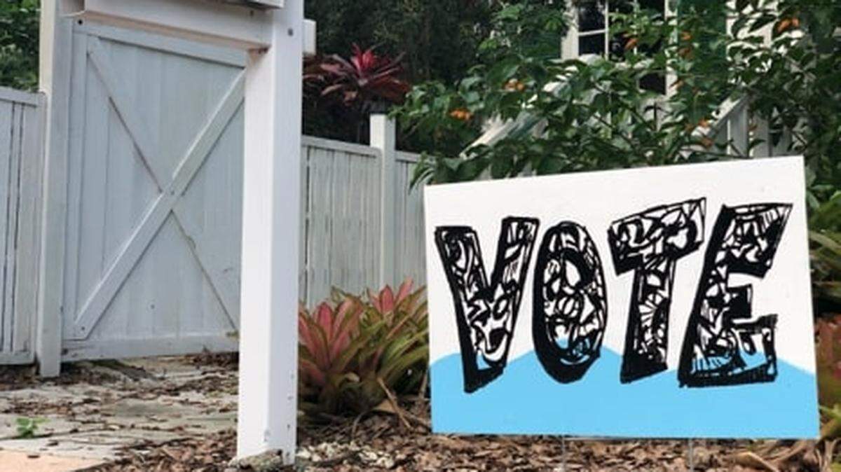 Artist Xavier Cortada’s yard sign encourages residents to vote with climate change in mind.