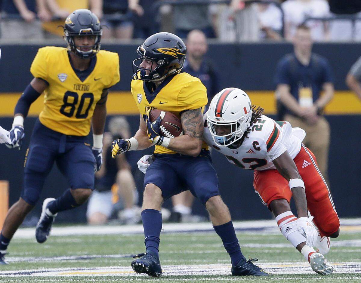 Toledo wide receiver Cody Thompson, center, is tackled by Miami defensive back Sheldrick Redwine (22) as Toledo’s Bryce Mitchell (80) looks on during the first half of an NCAA college football game Saturday, Sept. 15, 2018, in Toledo, Ohio.