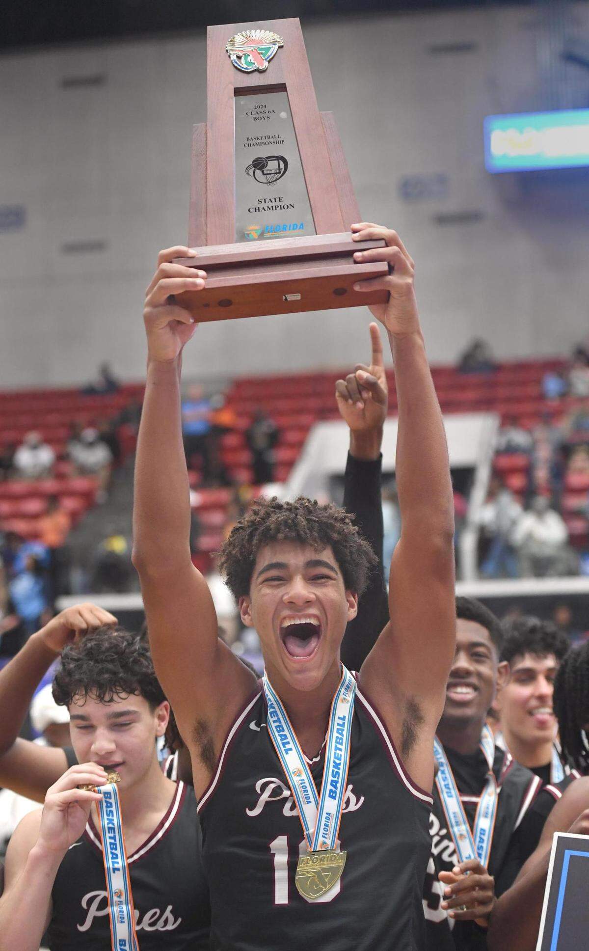 Pembroke Pines Charter’s Josh Harris (10) celebrates with the trophy after they beat Edgewater in the Class 6A final during the Florida High School State Championships at the RP Funding Center in Lakeland, Fl on Friday March 8, 2024. Pembroke Pines Charter defeated Edgewater 59-54 to win the Class 6A State Title. Scott Wheeler | Photo