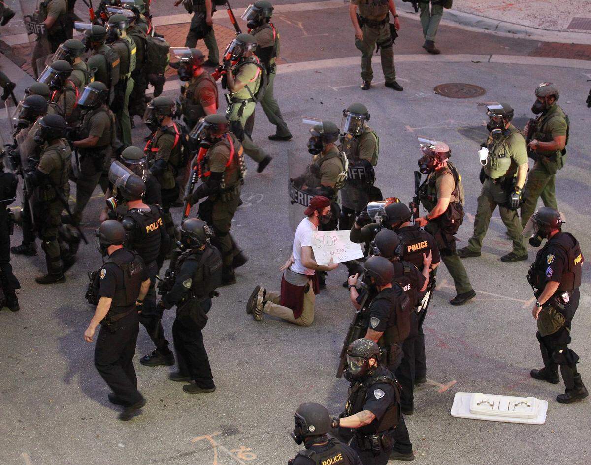 A man gets on one knee while police patrol the area during a protest near Wayne Huizenga Park in Fort Lauderdale. Thousands in South Florida have joined demonstrations that have spread across the country to call for an end to police brutality following the death of George Floyd while in police custody in Minneapolis.