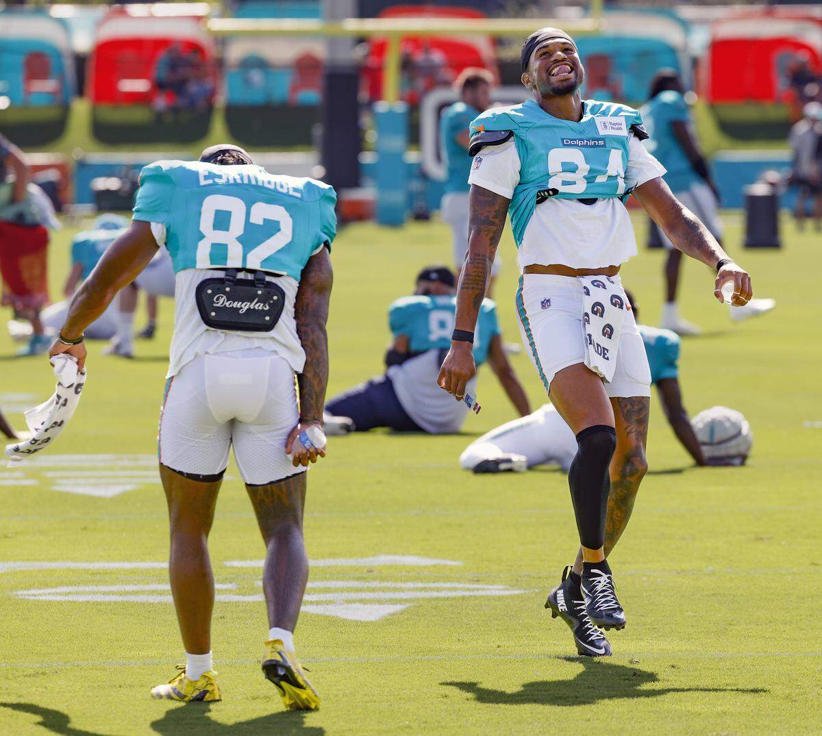 Miami Dolphins wide receivers Erik Ezukanma (84) and Dee Eskridge (82) dance on the field as the team arrives for an NFL football joint practice with the Jacksonville Jaguars.