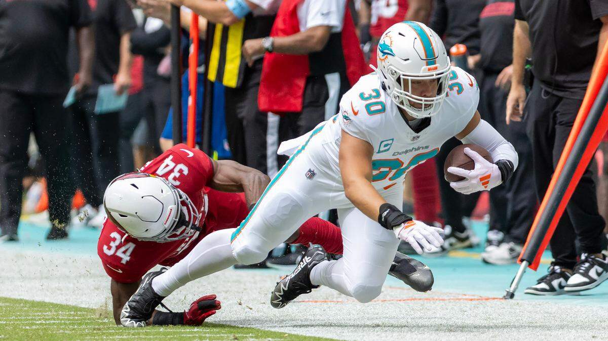 Miami Dolphins fullback Alec Ingold (30) runs for a first down as Arizona Cardinals safety Jalen Thompson (34) defends during the first half of an NFL game at Hard Rock Stadium on Sunday, Oct. 27, 2024, in Miami Gardens, Fla.