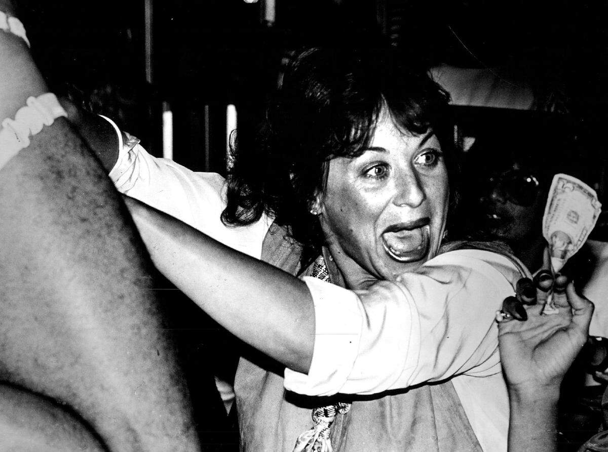 A customer at the Crazy Horse Saloon puts money in a dancer’s G-string in 1983.