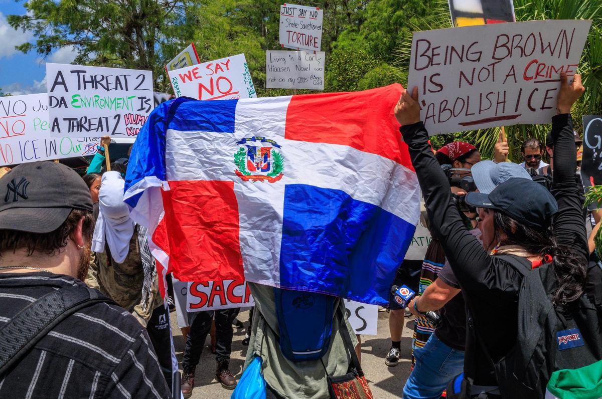 A Haitian flag is displayed as a group of people protested on US 41-Tamiami Trail while US President President Donald Trump and Florida Governor Ron DeSantis, toured the migrant detention center, dubbed “Alligator Alcatraz,” located at the site of the Dade-Collier Training and Transition Airport in Ochopee, Florida on July 1, 2025.