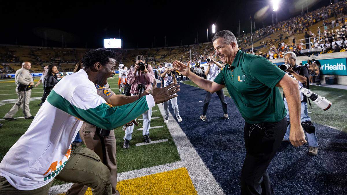 Miami Hurricanes head coach Mario Cristobal celebrates with former NFL player and Hurricane Michael Irvin after their team won their NCAA college football game against the California Golden Bears at the California Memorial Stadium on Saturday, Oct. 5, 2024, in Berkeley, Calif.