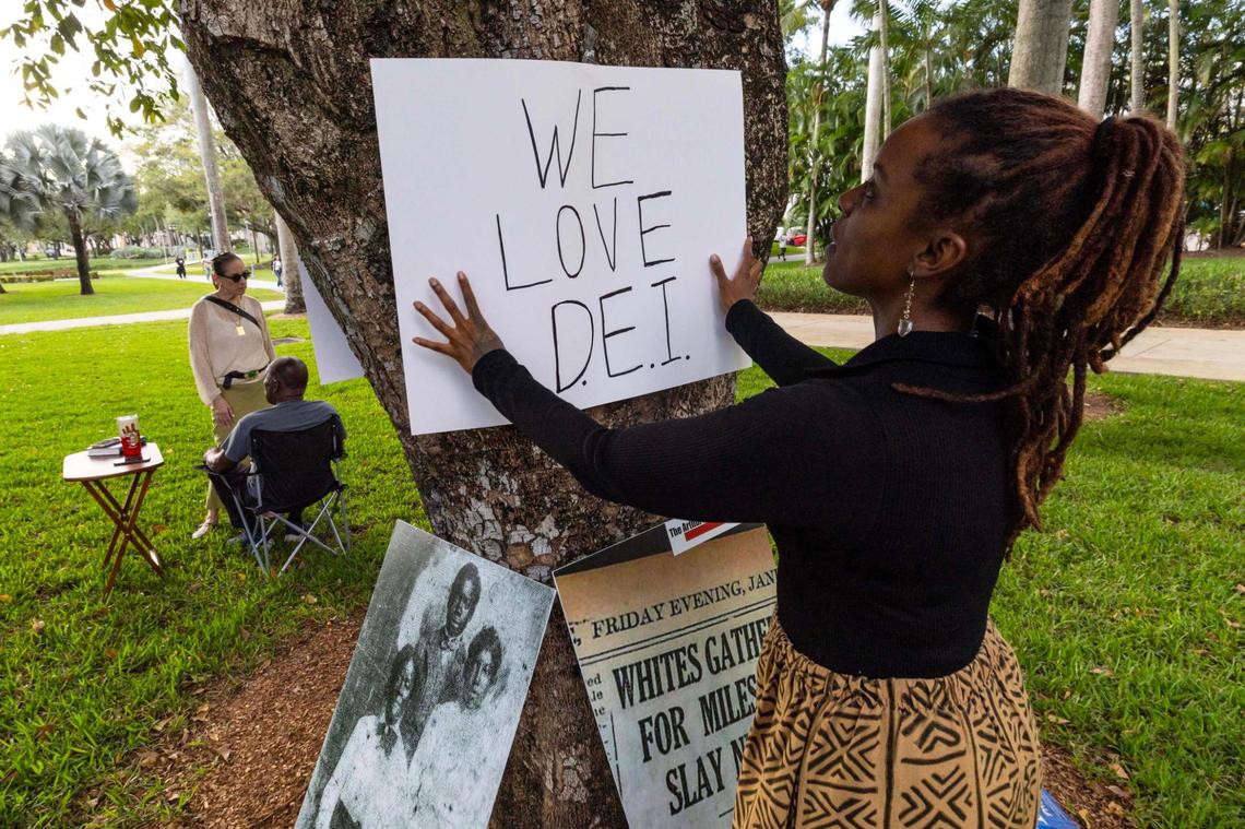 Artist and student Leah Gayle, 34, hangs a sign that reads “WE LOVE D.E.I.” before a “Black History Learning Tree” event at Florida International University on Tuesday, April 1, 2025, in Miami, Fla.