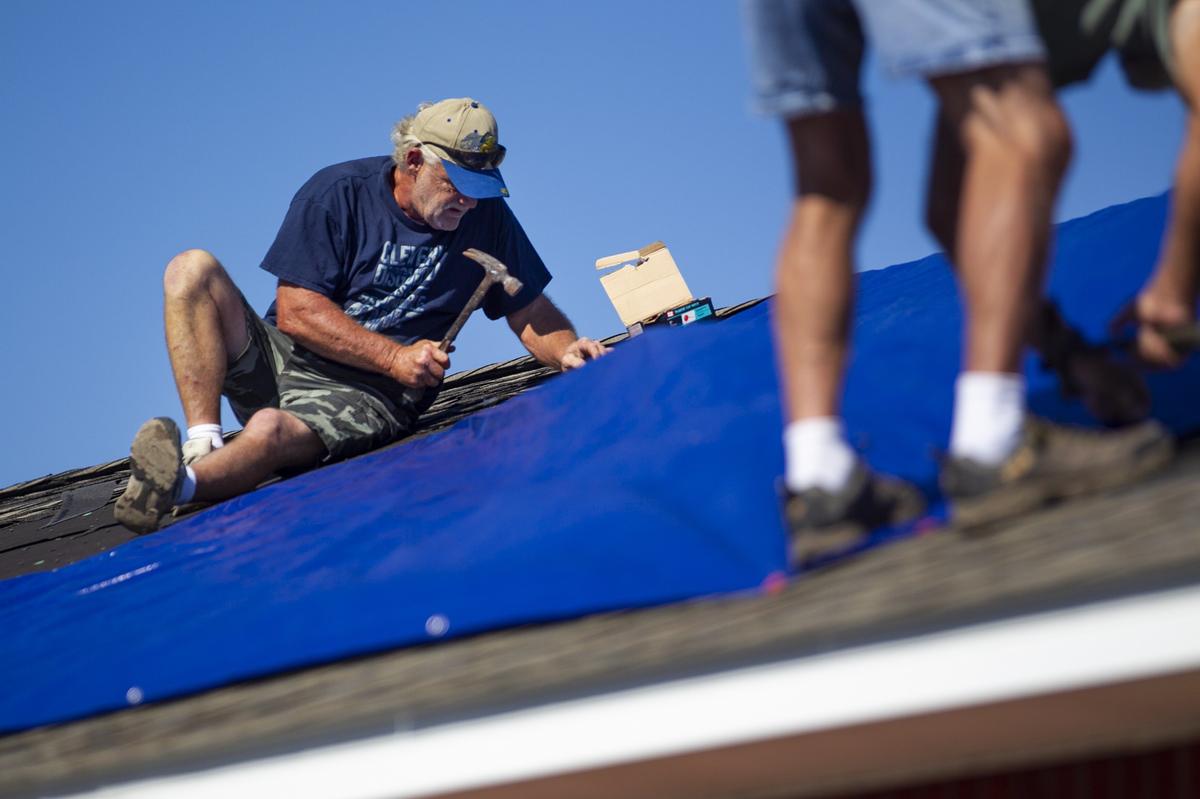 Tommy Chavis, left, and Bobby Brake fasten a blue tarp over a building in Port Saint Joe, Florida, eight days after Hurricane Michael devastated the area, leaving hundreds of thousands without shelter, power and food.