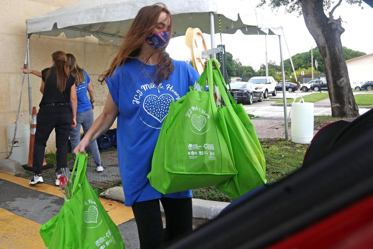 Lindsey Weingard loads bags of food gifts into the trunk of a car as the Jewish Community Services of South Florida and over five hundred volunteers provide much-needed connections and deliver 560 food gift baskets to homebound seniors in the community at the Annual Rosh Hashanah Milk & Honey event at the Michael-Ann Russell Jewish Community Center in Ojus, Florida, Sunday, September 13, 2020.