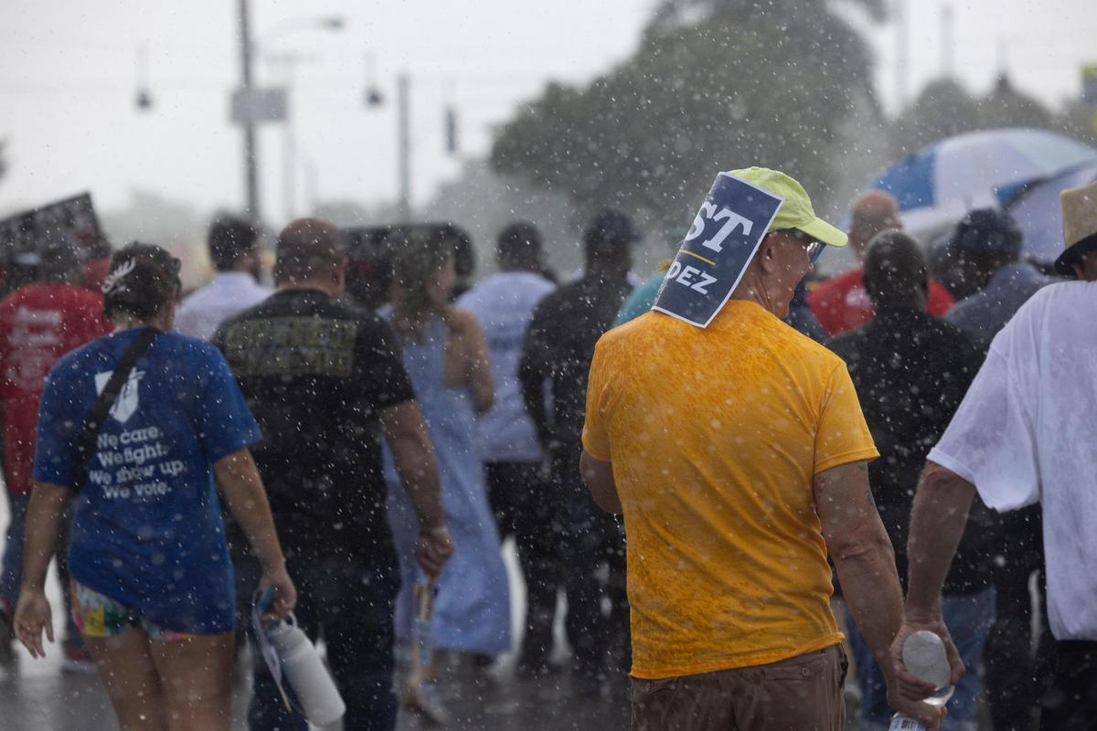 A man walks through the rain during a Souls to the Polls march on Sunday, Nov. 6, 2022, in Liberty City.