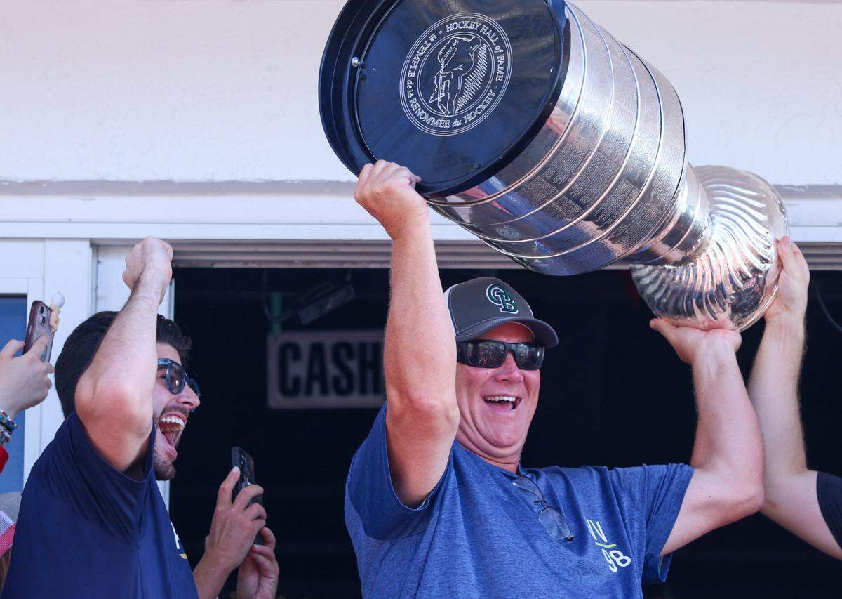 Former NHL player Keith Tkachuk, right, father of the Panthers’ Matthew Tkachuk, hoists the Stanley Cup to the cheers of fans at the Elbo Room in Fort Lauderdale, Florida on Wednesday, June 18, 2025.
