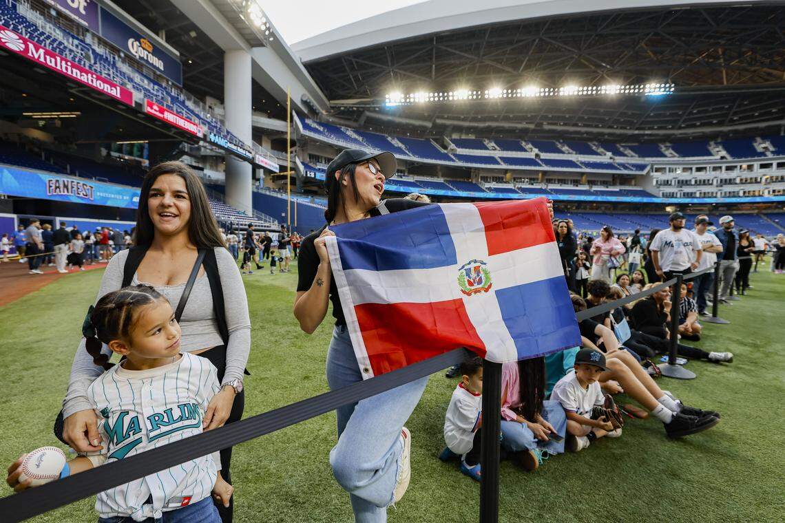 Silvina Leoni, 7, joins her mother Sarah Lanuza, as Elizabeth Valera waves the Dominican flag during Marlins Fan Fest.