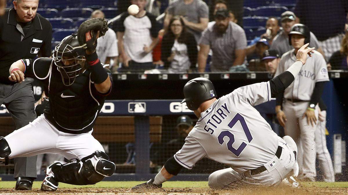 El receptor de los Marlins Jorge Alfaro no puede retener el tiro y anota el corrdor de los Rockies’ Trevor Story (27) este viernes en Miami.