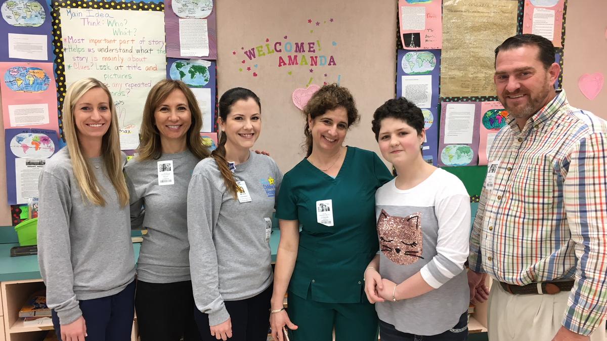 Amanda Aiello, second from right, stands between her parents, Shannon Aiello, left, and Dana Aiello, right, with members of a team from Broward Health's STARS program who helped her transition back to school after she beat cancer. They are, from left, Kasey Castro, a child life specialist, Joan Schreier, an art therapist, and Melissa Stachowiak, a Broward Health pediatric oncology social worker.