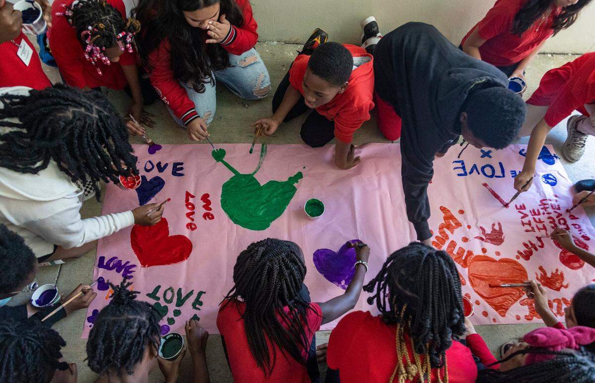 Students at Silver Lakes Middle School paint messages of love and friendship on paper during a ceremony in memory of those killed at Marjory Stoneman Douglas High School five years ago.
