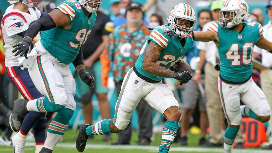 Miami Dolphins nose tackle Raekwon Davis (98) blocks New England Patriots quarterback Mac Jones (10) as Dolphins cornerback Xavien Howard (25) runs after intercepts the ball during the first quarter of an NFL football game at Hard Rock Stadium on Sunday, January 9, 2022 in Miami Gardens, Florida. (David Santiago Photo / Miami Herald)