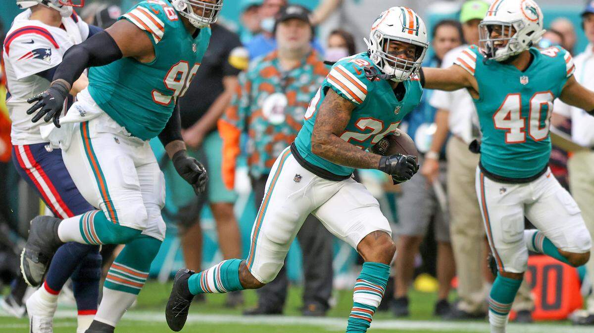 Miami Dolphins nose tackle Raekwon Davis (98) blocks New England Patriots quarterback Mac Jones (10) as Dolphins cornerback Xavien Howard (25) runs after intercepts the ball during the first quarter of an NFL football game at Hard Rock Stadium on Sunday, January 9, 2022 in Miami Gardens, Florida. (David Santiago Photo / Miami Herald)