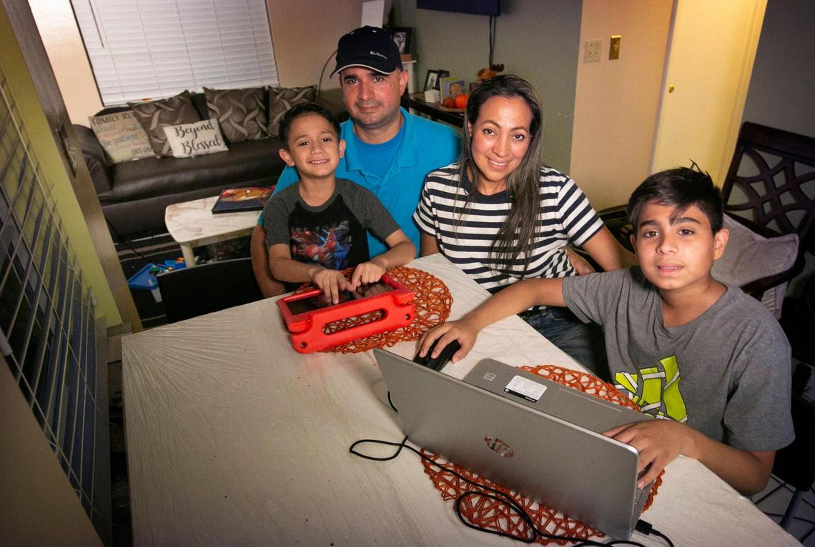Mateo Acuna, 6, Juan Acuna, 45, Ana Alvarez, 48, and Juan David Acuna, 13, sit in their newly furnished apartment while the children work on a tablet and a laptop, all courtesy of generous donors to the Wish Book program. The family is very grateful to have received so much from generous donations to the Wish Book program last holiday season.