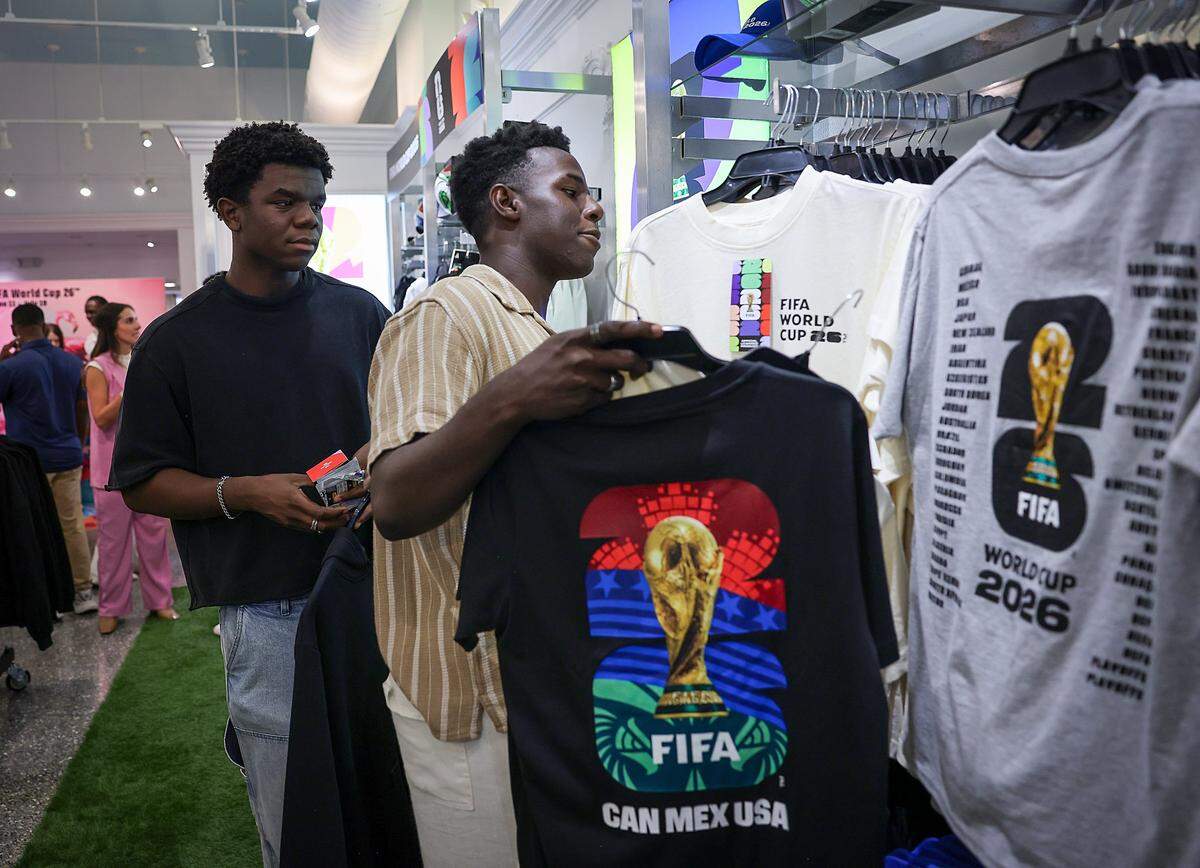 Brothers Gaethan, left, and Brian Lafortune select FIFA merchandise, limited to $200, on Monday in Miami Beach.