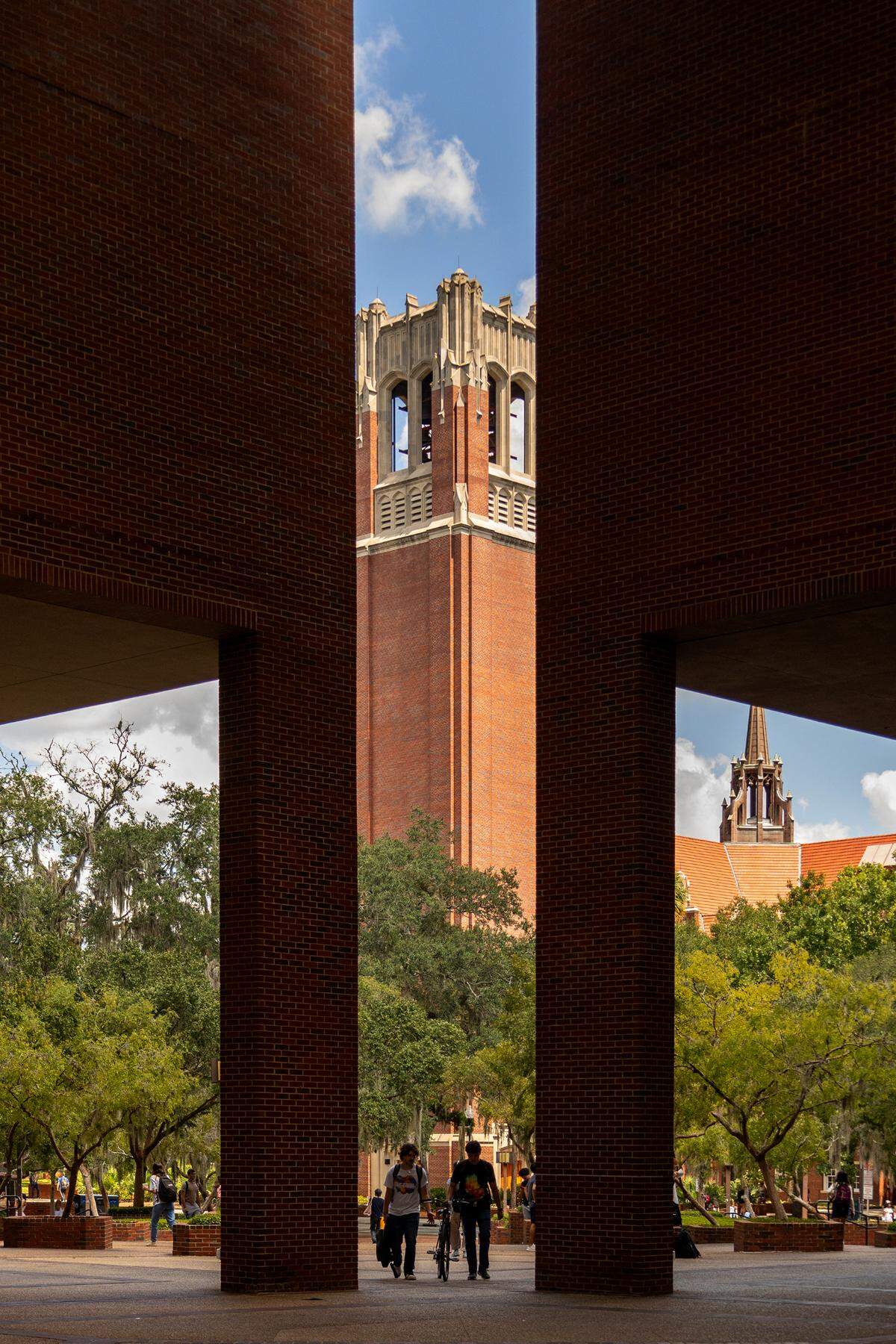 Students walk near the 157-foot tall Century Tower at the University of Florida in Gainesville. A University of Florida researcher and an unspecified number of students have been implicated in an illegal scheme investigated by the Justice Department to fraudulently buy biochemical products that were delivered to a UF laboratory over seven years before they were illegally shipped to China, according to federal court records. (Gabriel Velasquez-Neira/Fresh Take Florida)