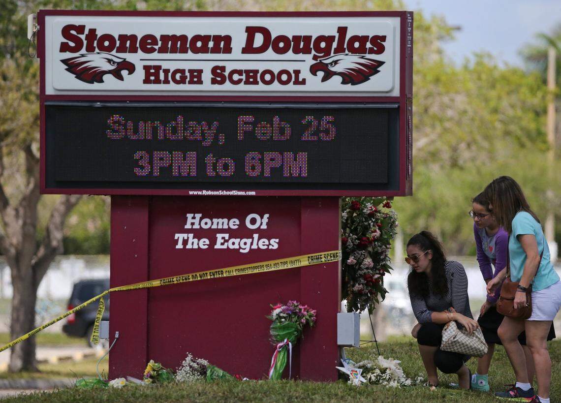 Mourners bring flowers as they pay tribute at a memorial for the victims of the shooting at Marjory Stoneman Douglas High School on Sunday, Feb. 25, 2018. Parents and students returned to the school for the first time since 17 people were killed in a mass shooting at the school in Parkland on Feb. 14.