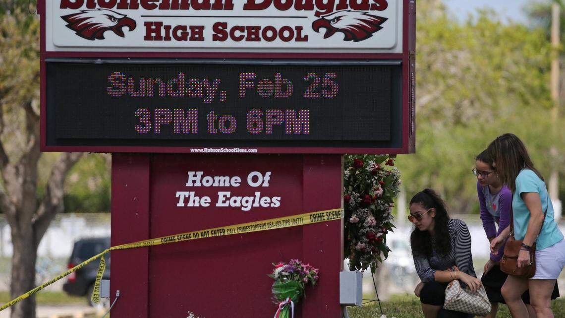 Mourners bring flowers as they pay tribute at a memorial for the victims of the shooting at Marjory Stoneman Douglas High School on Sunday, Feb. 25, 2018. Parents and students returned to the school for the first time since 17 people were killed in a mass shooting at the school in Parkland on Feb. 14.