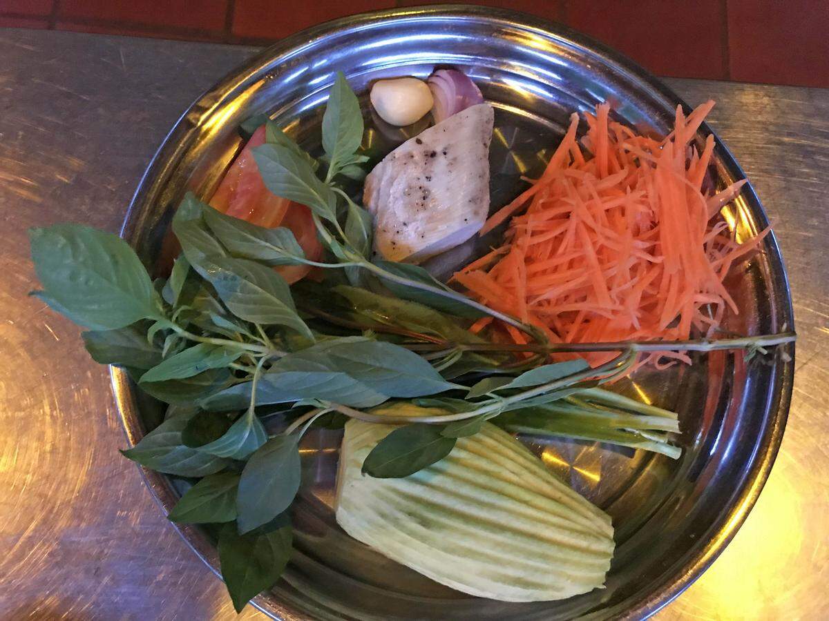 Ingredients for a Cambodian salad include green mango, carrots, chicken, tomato, basil, shallots, garlic and other seasonings.