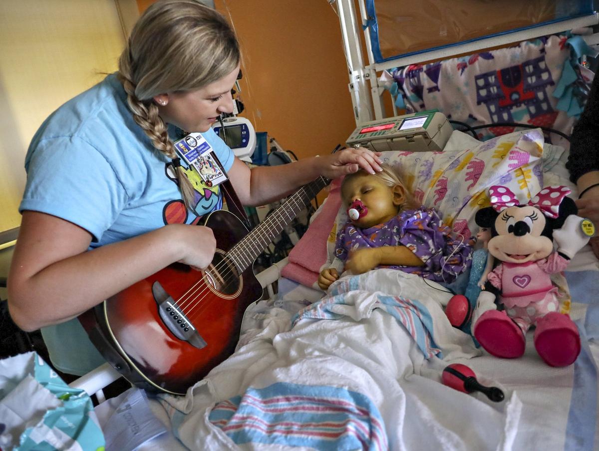 Music therapist Stephanie Epstein stands bedside by Elizabeth Foley, 2, who suffers from Alagille Syndrome, and strokes her head as she begins to relax and fall asleep on Tuesday, October 1, 2019, at Holtz Children’s Hospital, part of the UM Jackson Health System in Miami.