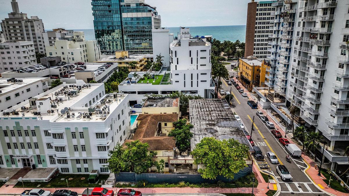 Vista aérea de una parcela en esquina con dos edificios en un distrito histórico de Miami Beach, en Indian Creek Drive, donde un urbanizador planea elevar y restaurar un edificio de apartamentos de 1936 para protegerlo del aumento del nivel del mar y convertirlo en la pieza central de la remodelación de un edificio de condominios de lujo. El edificio está en el centro con el tejado oscuro.