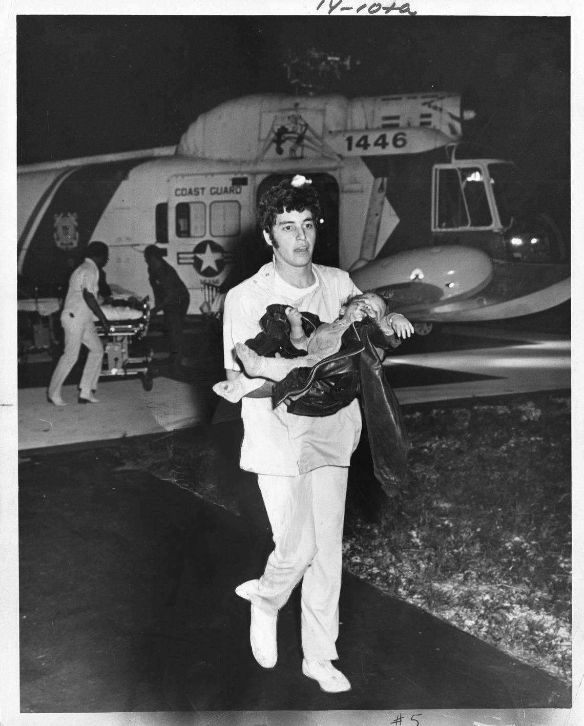 Bill Sanders / Miami Herald staff - infant Miguel Angel Junco brought in by survivor Siminerio. This baby, bleeding from face and mouth cuts, was carried from the crash by another suvivor -- martin Siminerio (whom we also have art of) -- Fate of the infant’s parents was unknown after he was broght into Palmetto Hospital by rescue copter. he was treated and sleeping in a crib awaiting word of his parents Saturday morning. he’s between 15 and 18 months old, hospital officials estimated.