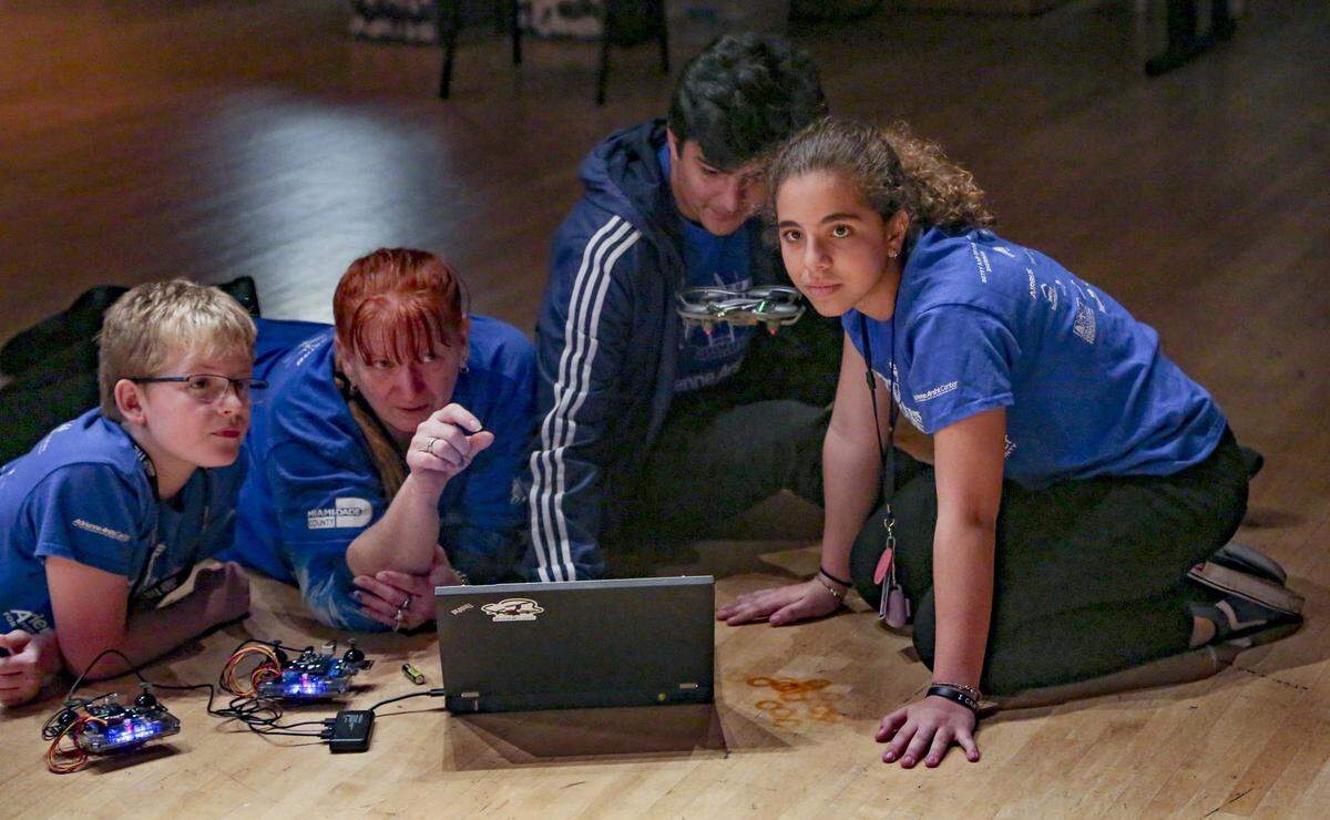 South Miami Middle School students Casey Golden, left, and Michelle Flores, right, get assistance from teacher Suzanne Banas and FIU teacher assistant Oward Cadenas, second from right, as they watch and program a drone in flight at the Adrienne Arsht Center for the Performing Arts during the second season of Kitty Hawk, a STEAM-focused (Science, Technology, Engineering, Arts, Math) program that is part curriculum and part performance.