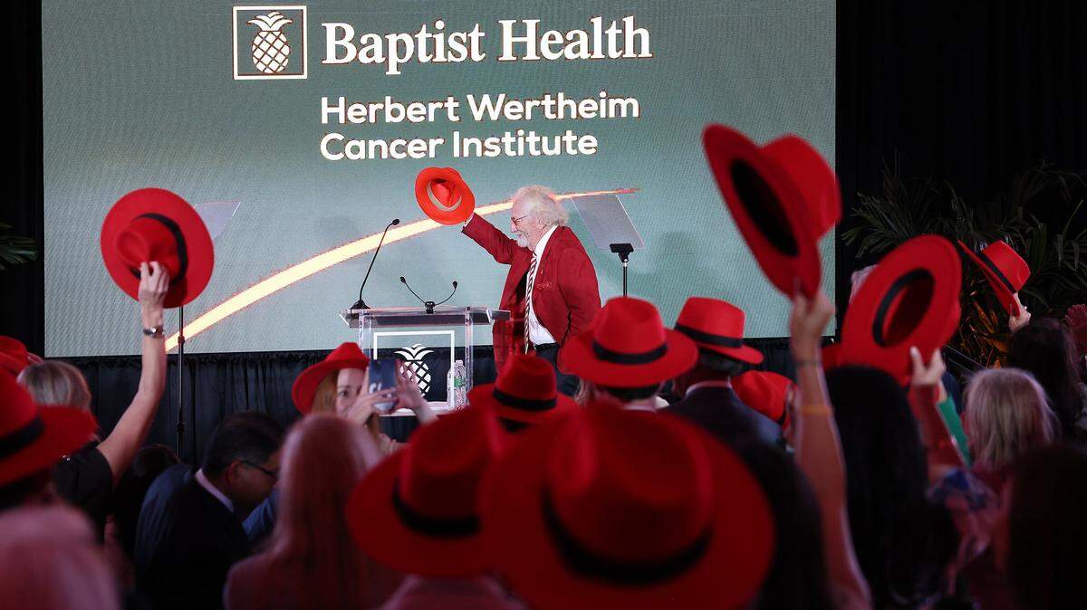 Attendees raise their hats as Dr. Herbert Wertheim takes the stage during the celebration of his historic philanthropic gift and the naming of the Herbert Wertheim Cancer Institute at Baptist Health. Baptist Health South Florida and the Baptist Health Foundation announced the largest single philanthropic gift in the organization's 66-year history from Dr. Herbert Wertheim during a celebration of the donation and Wertheim's upcoming birthday at Baptist Health in Kendall, Wednesday, May 20, 2026, in Miami, Florida. Attendees donned red hats-a signature of Dr. Wertheim-in tribute to his visionary philanthropy and in recognition of his lasting impact on the Baptist Health and FIU.