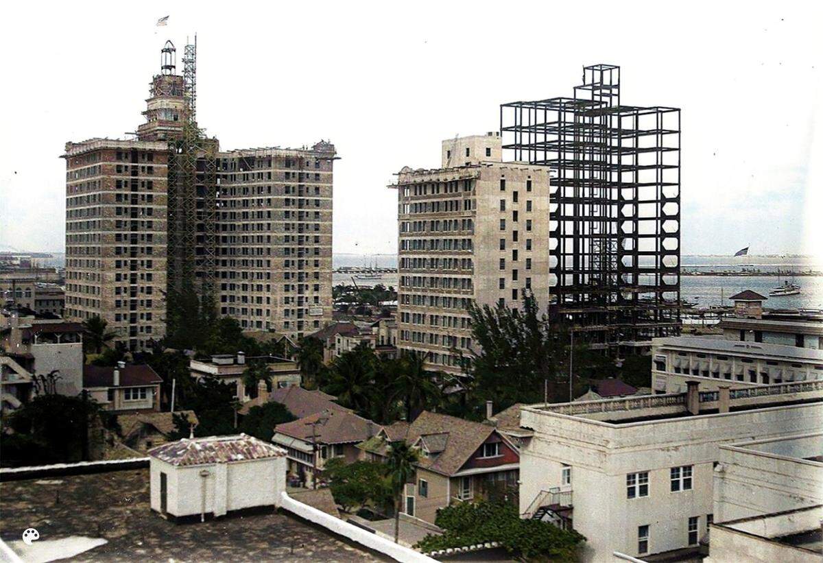 Esta fotografía coloreada de 1925 muestra la estructura de acero del Watson Hotel, más tarde conocido como Miami Colonial Hotel, mientras el edificio estaba en construcción en el downtown de Miami. El edificio de oficinas Exchange, de 1923, está justo detrás. A la izquierda, el Everglades Hotel.