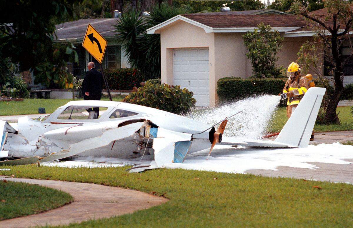 A Pembroke Pines fireflghter sprays down a single-engine plane that crash-kanded into a neighborhood just north of Perry Airport on May 14, 1996. The plane clipped a house and then landed in the street. The pilot was taken to Memorial Hospital.