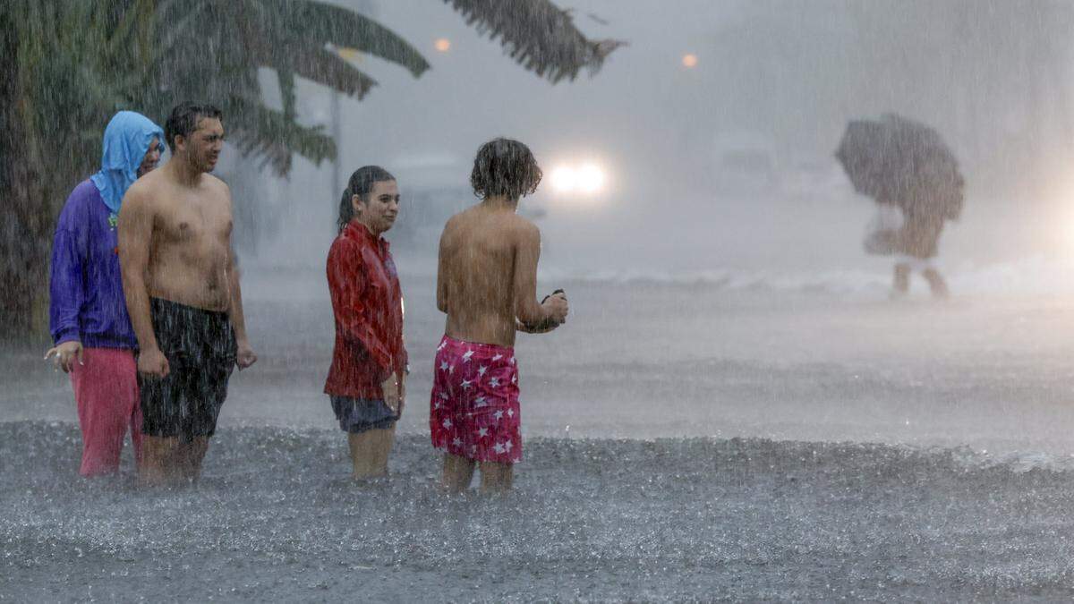 People attempt to cross a flooded street North Beach in Miami Beach on June 12, 2024. 