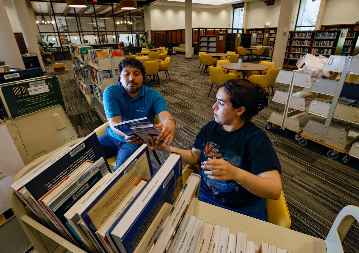 Andrés Martínez y María Vázquez desempaquetan libros en la Biblioteca de Coral Gables mientras ayudan a preparar la reapertura el lunes 22 de mayo después que la biblioteca cerró por renovaciones en 2021. Al Diaz adiaz@miamiherald.com