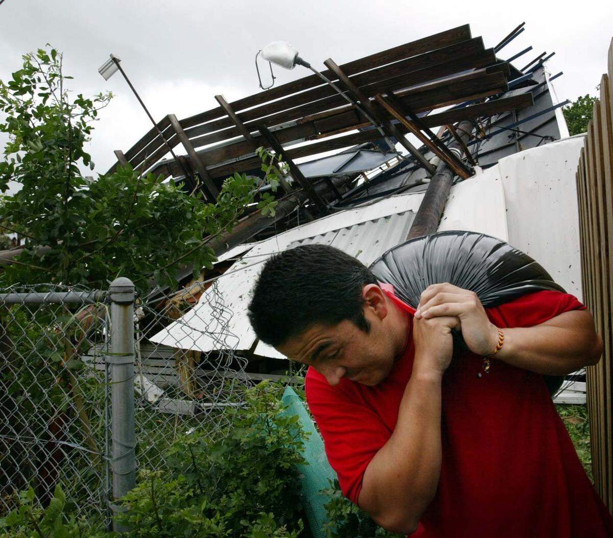 In 2004, Hugo Pinto carries his belongings outof his mobile home in Lantana after a billboard fell on top of his home during Hurricane Frances. No one was home at the time that the billboard, advertising Bubba Burgers, crashed down on top of his home.